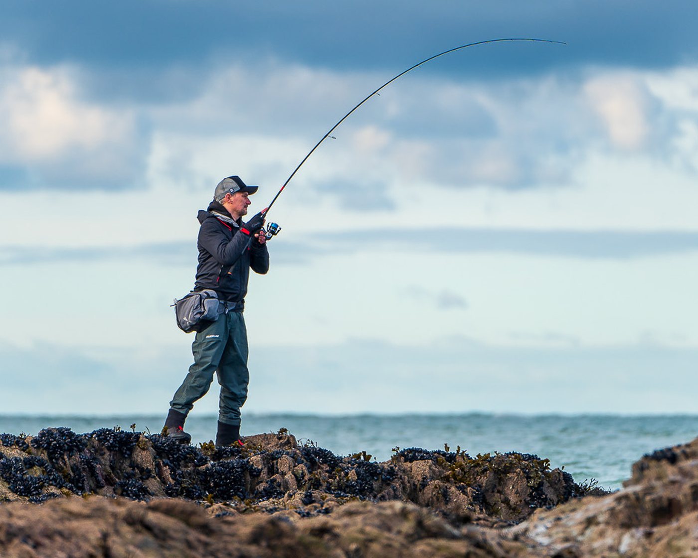 Ben Field on the rocks with a lure rod hooped over